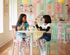 Two children sitting at a table in a colorful playroom.