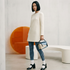 Woman in a white mod dress and houndstooth tights standing in a modern interior setting.