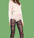 Person wearing a light pink sweater and black lace tights on a plain background