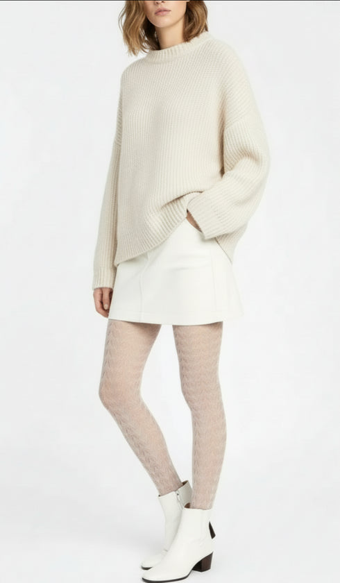 Person wearing a cream sweater, white skirt, white tights, and white boots on a white background