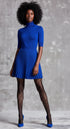 Woman wearing a blue dress and tights against a gray background