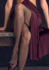 Person wearing fishnet stockings and a burgundy dress sitting on a bench.