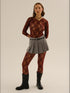 Woman wearing wine colored lace tights with grey skirt. studio soft light backgound