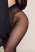 Black sheer stockings worn with a black outfit on a beige background