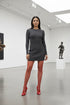 Woman in a gray dress and red shoes standing in an art gallery.