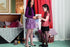 Two young girls in a room with a red curtain and decorative items. wearing floral patterned tights