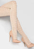 Beige over-the-knee textured tights worn with high-heeled shoes on a light gray background