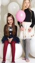Two young girls in front of white balloons, one holding a pink balloon.