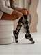 Person wearing BROWN and gray argyle patterned knee-high socks sitting on a white surface.