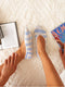 Light blue ankle socks with white stripes are worn on a textured cream rug, next to an open book and magazine.